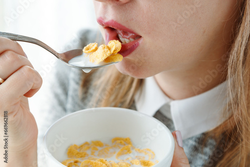 Closeup of mouth-eating corn flakes with milk on breakfast, unrecognizable woman. Concept of healthy eating.