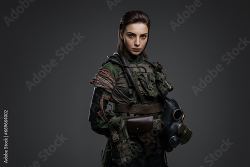 Portrait of a woman in military attire, portraying a rebel or partisan, against a gray background, depicting a Middle Eastern conflict