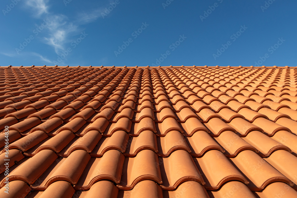 Clay tile roof close-up. New roofing made of orange clay tiles with blue sky in the background, free space for text, copy space - obrazy, fototapety, plakaty 