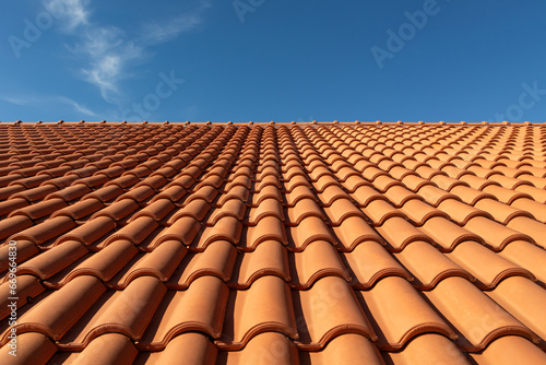 Clay tile roof close-up. New roofing made of orange clay tiles with blue sky in the background, free space for text, copy space photo