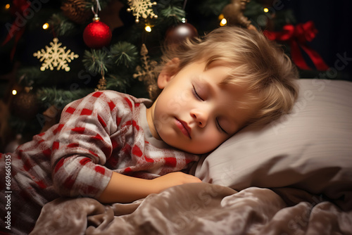 Waiting for Santa Claus. Adorable little Caucasian little boy sleeping on the background of Christmas tree. © ribalka yuli