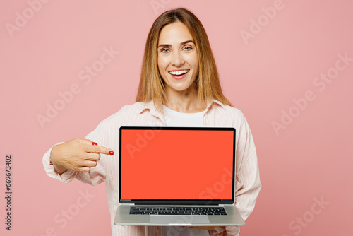 Full body fun young IT woman she wears shirt white t-shirt casual clothes hold use work point finger on blank screen workspace area laptop pc computer isolated on plain pastel light pink background. photo