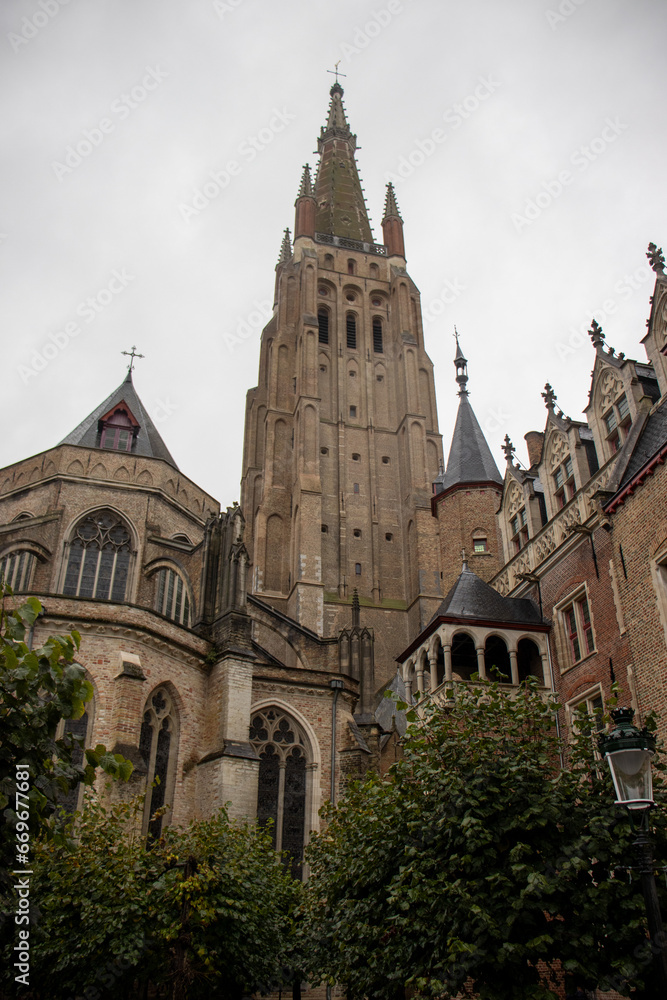 The Towering Spire of the Church of Our Lady in Bruges Against a Cloudy Sky - Medieval Brickwork Marvel