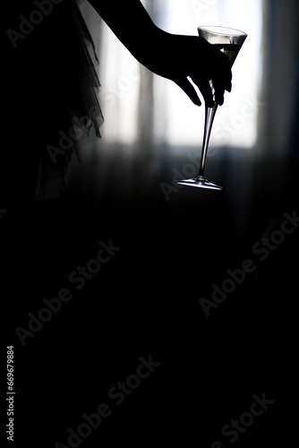 Silhouette of a Hand Holding a Cocktail Glass Against a Backlit Window