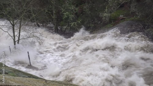 River overflowing and with high water flow and force due to heavy rains causing flooding