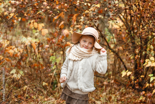 Portrait of a smiling young girl in a hat in an autumn park.
