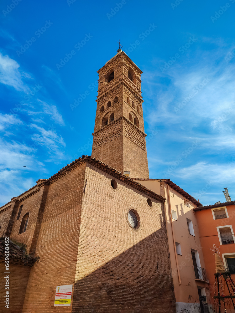 Impressive architecture of ancient Roman Catholic Cathedral Santa Maria de Huerta in Tarazona with dome tower decorated with turrets in Aragonese Mudejar style against blue sky on sunny day, Spain