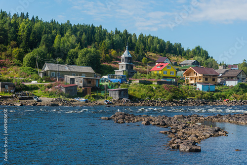 rapids on the Umba River, Kola Peninsula, Russia, against the background of the old Pomeranian village of Umba photo