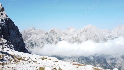 Majestic high mountain peaks in Alpes with misty clouds beneath in a valley and light blue clear sky above. Triglav mountain, Slovenia. photo