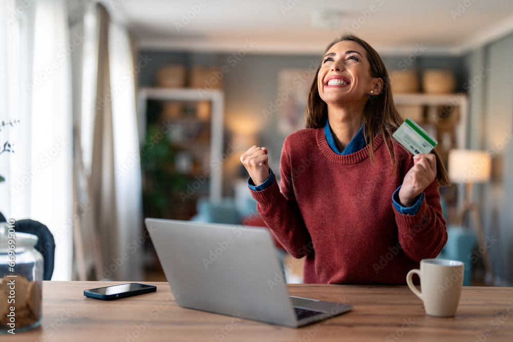 Φωτογραφία Joyful businesswoman feeling excited holding credit card sitting at desk with laptop screaming with happiness