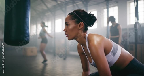 Woman, breathing and tired after boxing in gym for fitness, wellness and fight with punching bag and power. Health, exercise and self defense, recover from sports workout with sweat and boxer athlete