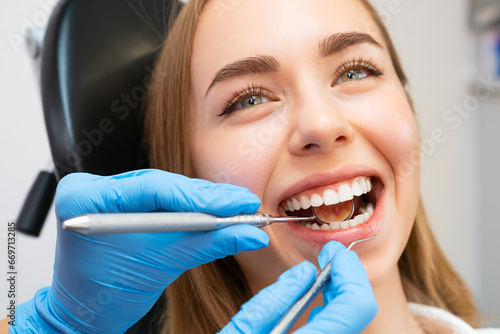 The dentist, wearing gloves, uses a small mirror and dental probe to inspect the patients teeth and gums
