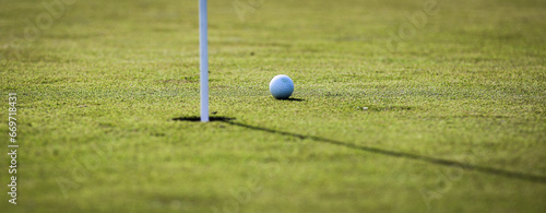 White golf ball next to putting green hole waiting to be tapped in at a golf course in Central Florida