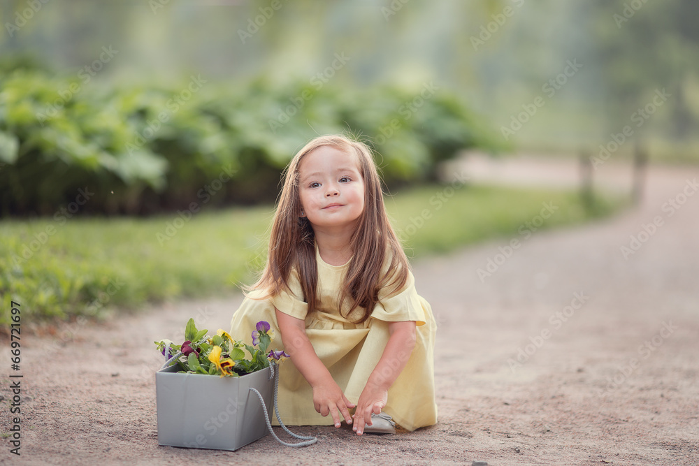 Little girl gardener with flowers in summer