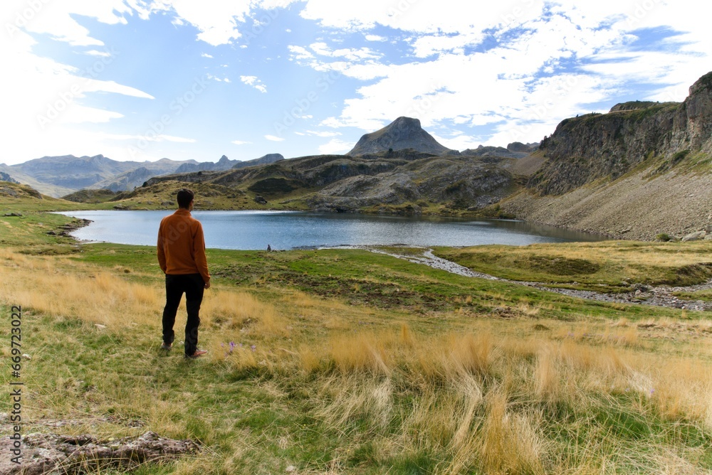 man looking at the grandeur of a high mountain lake in the french pyrenees man looking at the grandeur of a high mountain lake in the french pyrenees