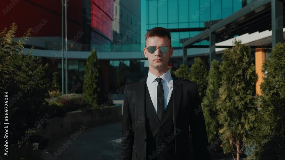 Against a backdrop of modern office buildings, a young Caucasian American man in a business suit portrays the image of a professional and driven entrepreneur. Against a backdrop of modern office buildings, a young Caucasian American man in a business suit portrays the image of a professional and driven entrepreneur.
