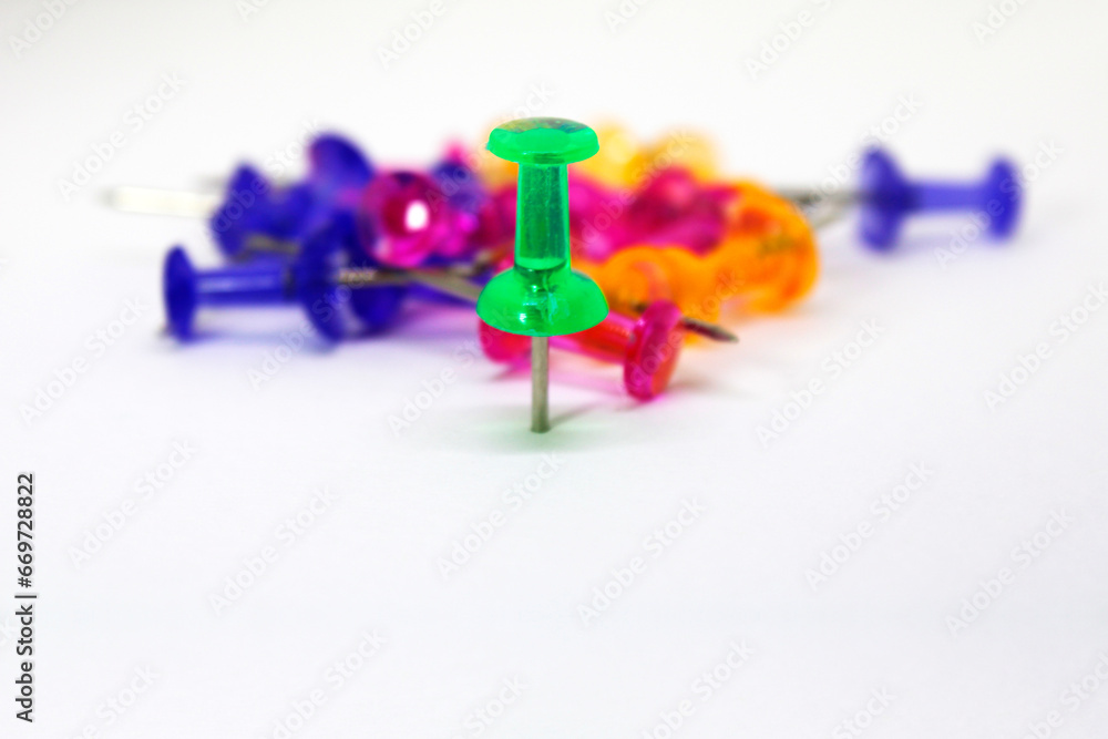 Firm green leader in front of fallen group of different colored thumbtack Firm green leader in front of fallen group of different colored thumbtack