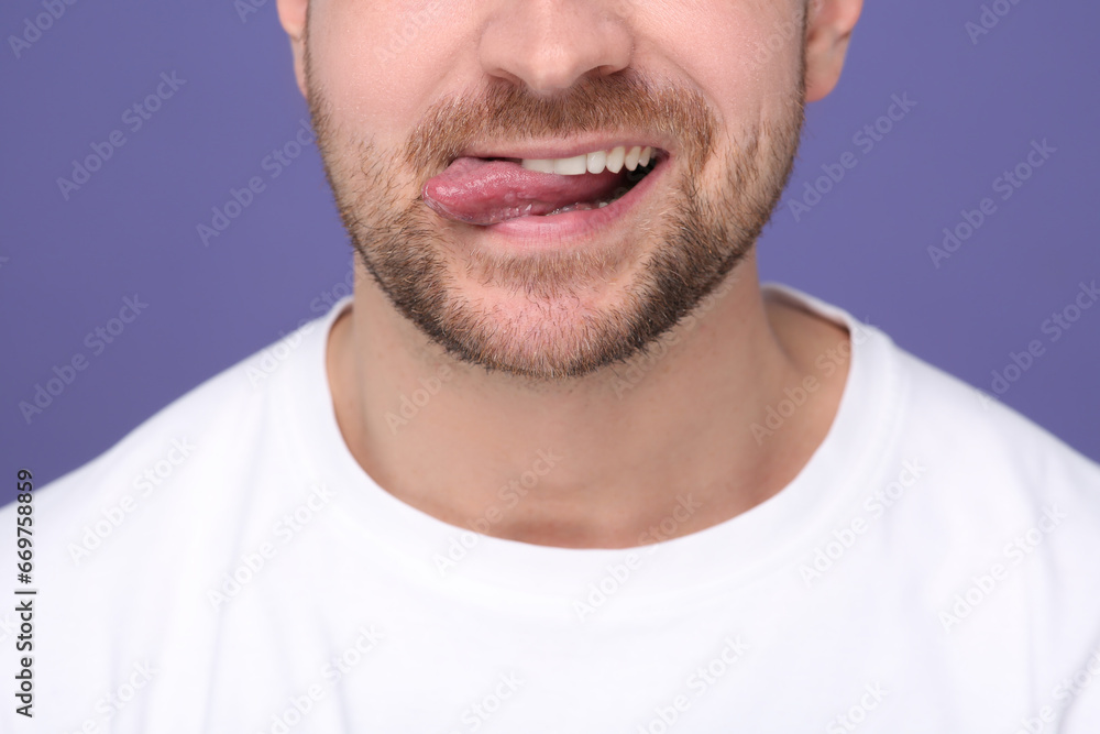 Obraz premium Man showing his tongue on purple background, closeup