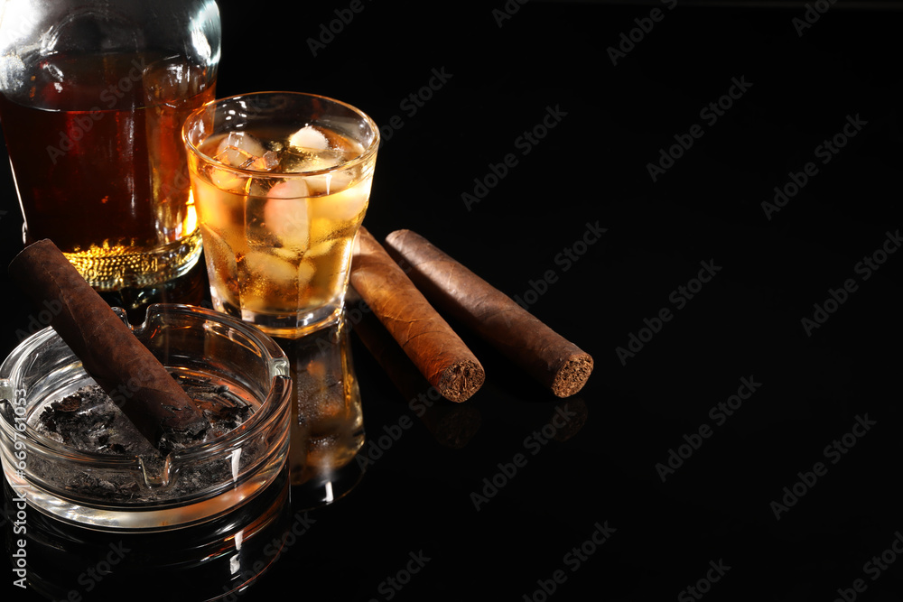 Smoldering cigar, ashtray and whiskey on black mirror surface. Space for text - obrazy, fototapety, plakaty 