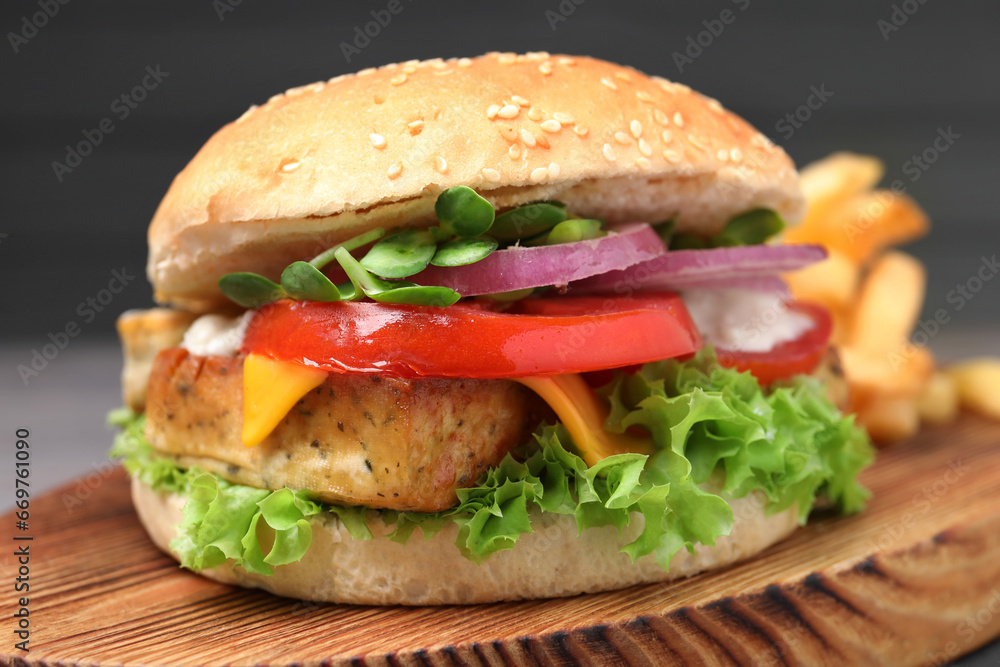 Delicious burger with tofu and fresh vegetables on wooden board, closeup Delicious burger with tofu and fresh vegetables on wooden board, closeup