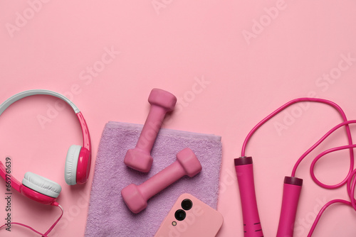 Flat lay composition with dumbbells and smartphone on pink background. Space for text