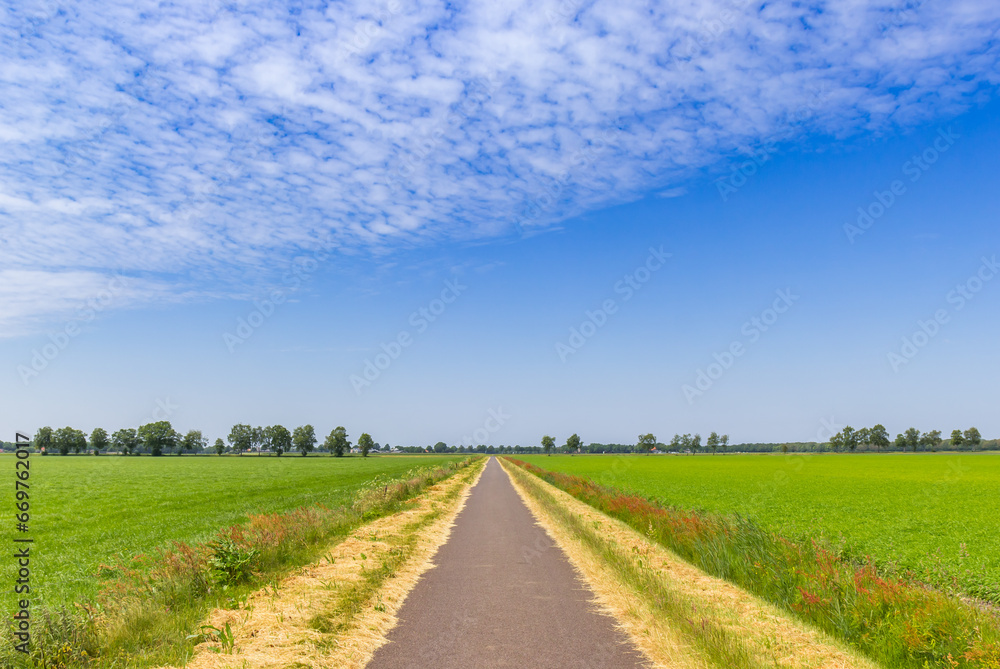 Straight road going through the flat landscape of Drenthe, Netherlands Straight road going through the flat landscape of Drenthe, Netherlands