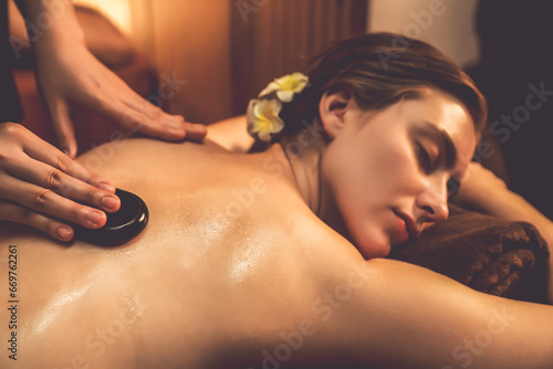 фотографія Hot stone massage at spa salon in luxury resort with warm candle light, blissful woman customer enjoying spa basalt stone massage glide over body with soothing warmth