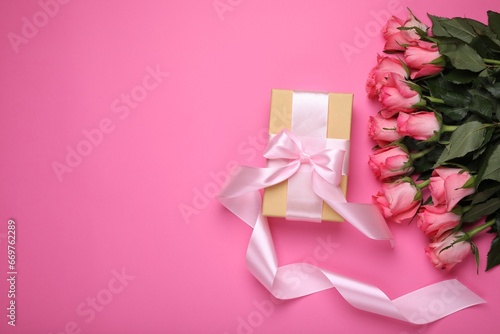 Gift box and beautiful flowers on pink background, flat lay. Space for text © New Africa