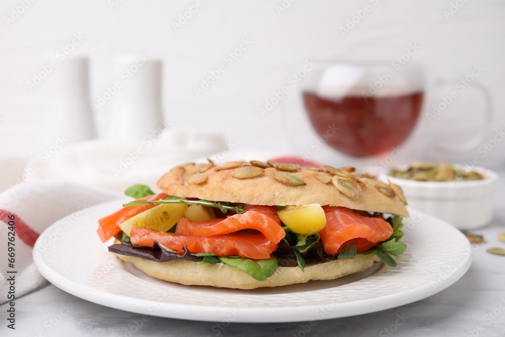 Tasty bagel with salmon and tomatoes on white marble table, closeup
