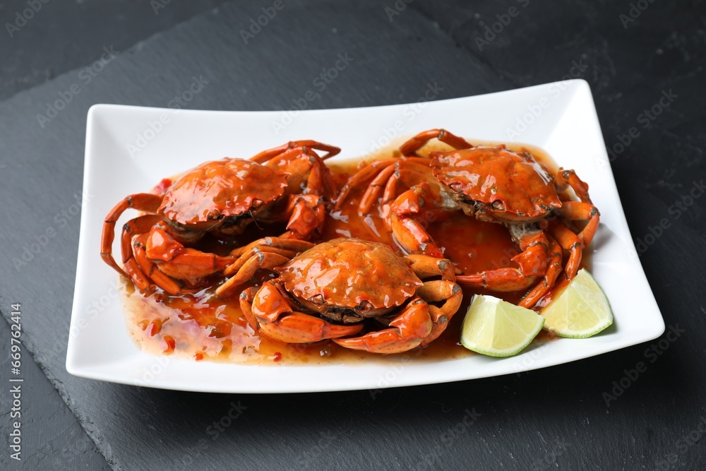 Delicious boiled crabs with sauce and lime on black textured table Delicious boiled crabs with sauce and lime on black textured table