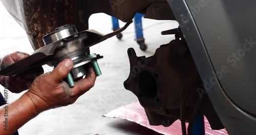 Close up Mechanic man hands repairing car auto repair shop uses jack change tyre. Man hands fixing Shock absorber machinery vehicle mechanical service. Vehicle Car overhaul maintenance engineer