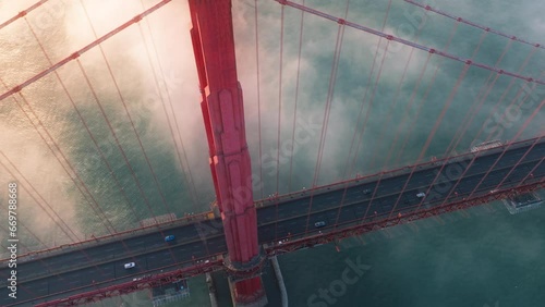 Breathtaking aerial of cinematic Golden Gate at sunset. Cars driving by red bridge covered in scenic clouds. Karl the Fog drifting below red bridge main landmark of San Francisco California USA 4K