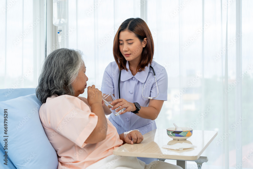 Obraz premium Elderly Asian patient admitted to hospital The nurse gave him water at the end of the meal.