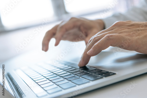 Closeup of businessman's hands typing on a laptop computer for data input and analysis in business performance and investment photo