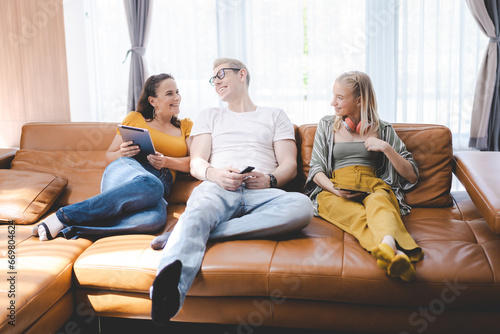 Happy young family enjoy lunch together at home using mobile phone. Addicted online social media cellphone people in living room and watching display having fun. Concept of addiction smartphone