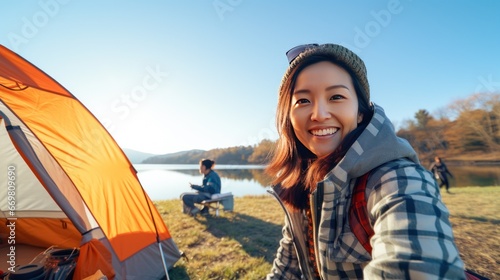 Smiling Asian female tourist brings family Camping by the lake. photo