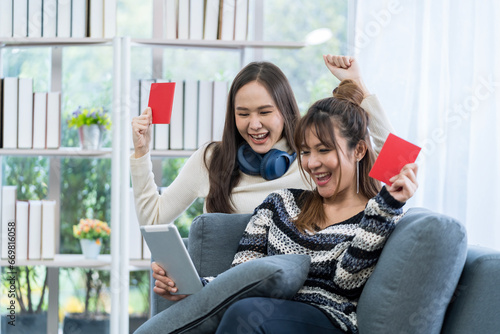 Two happy Asian women booked a hotel room. Concept of travel in summer and holiday. Two Asian woman planning a trip and holding a passport in the living room.