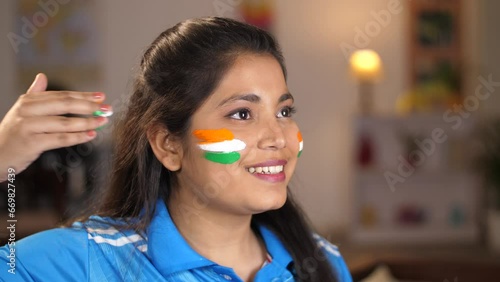 Closeup shot of a woman painting Tiranga on her face with a wide smile -patriotism  cricket fan  sports fan  Indian fan  support for India. Indian female with a proud gesture - India  Indian cricke... photo