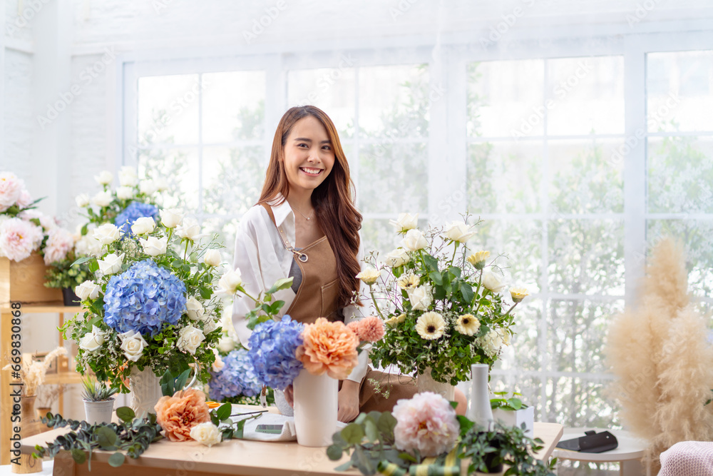 happiness smiling young lady making flower vase.Self employed florist working at flower shop.young asian florist making list from client order to arrange flower bouquet vase delivery
