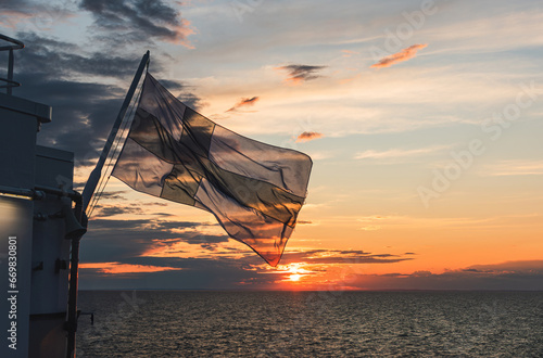 flag of Finland over the Gulf of Bothnia on the background of sunset