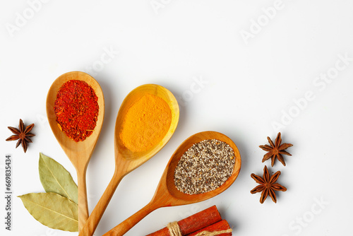Spice in wooden spoons on white background