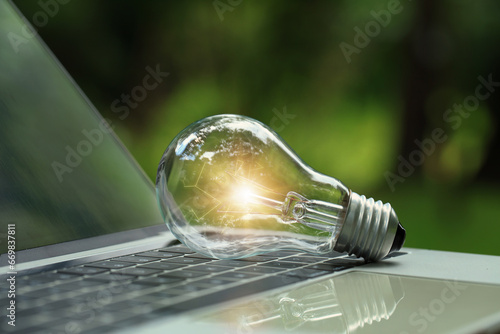 Renewable Energy.Environmental protection, sustainable energy sources. light bulb on a laptop with a green background that represents green energy,  and green technology for saving energy. photo