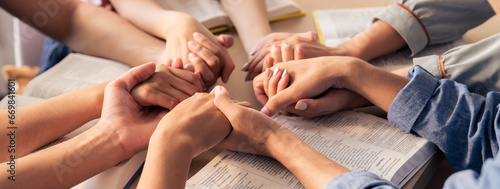 Cropped image of diversity people hand praying together at wooden church on bible book while hold hand together with believe. Concept of hope, religion, faith, god blessing concept. Burgeoning.