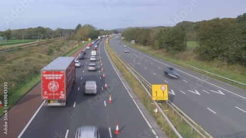 Slow moving traffic on English motorway with train passing on left. Time lapse 15x. M6 motorway, North Lancashire, England, UK. photo