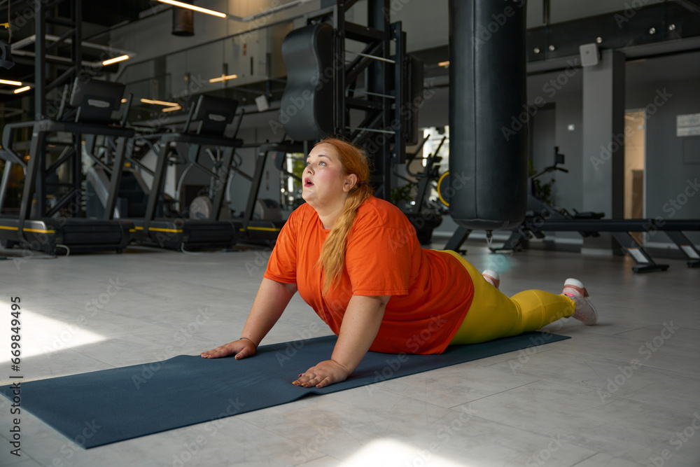 Fototapeta premium Obese woman enjoying stretching routine after hard abs crunch training
