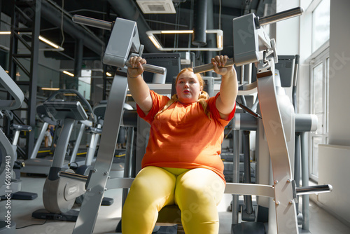 Beautiful young chubby woman working out on fitness gym equipment photo