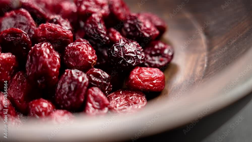 Red dried cranberries in a wooden brown bowl close up. Rotation. Nutritious culinary ingredients Red dried cranberries in a wooden brown bowl close up. Rotation. Nutritious culinary ingredients