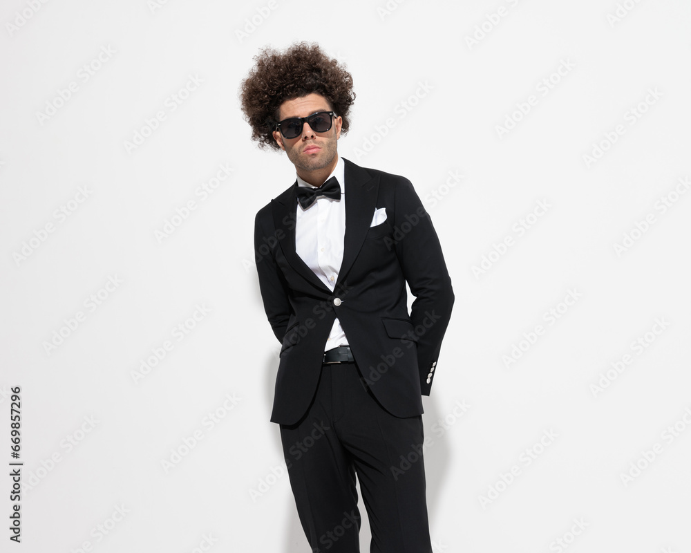 confident businessman with sunglasses in tuxedo holding hands behind confident businessman with sunglasses in tuxedo holding hands behind