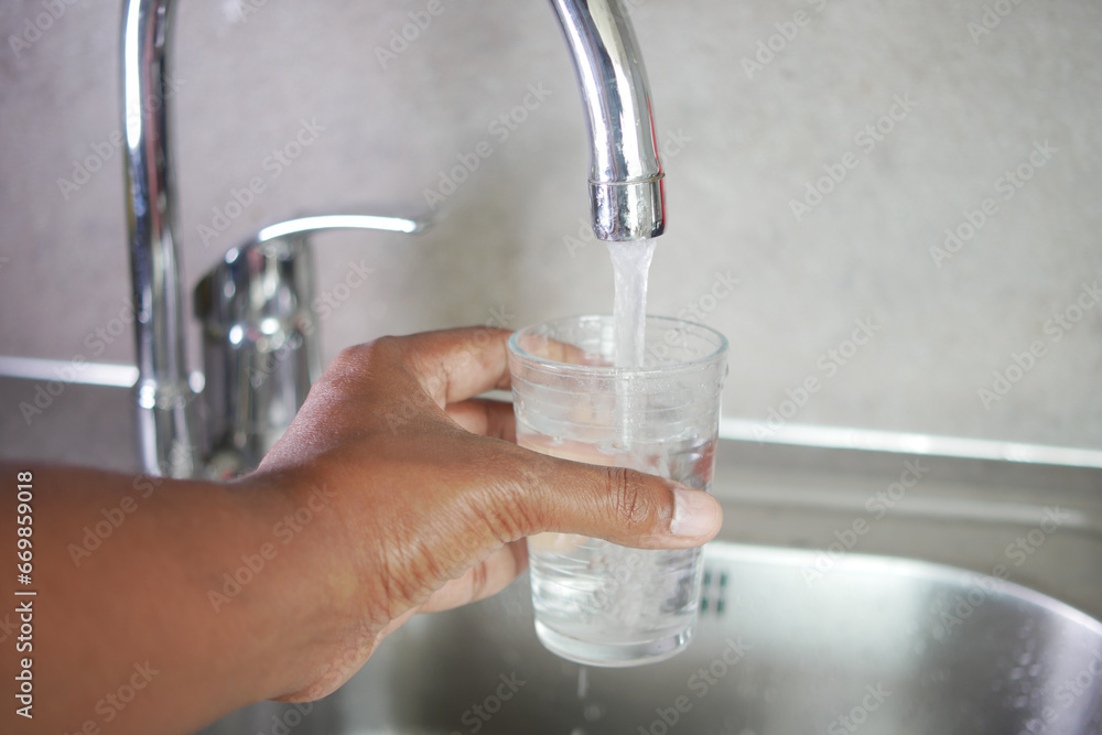 water pouring from a faucet tap in a glass, drinking pure water concept water pouring from a faucet tap in a glass, drinking pure water concept