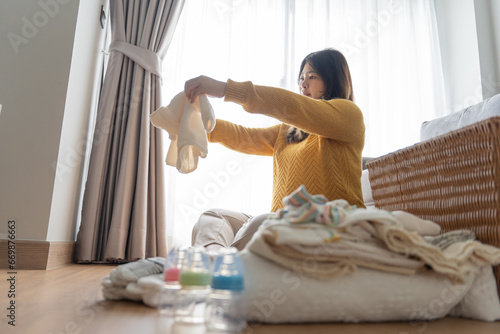 Pregnant asian woman getting ready for the maternity hospital preparing and planning baby clothes for new baby of pregnancy packing for maternity hospital at home photo